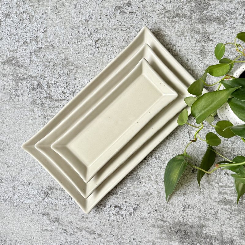 Stacked white rectangular serving trays with trailing plant.