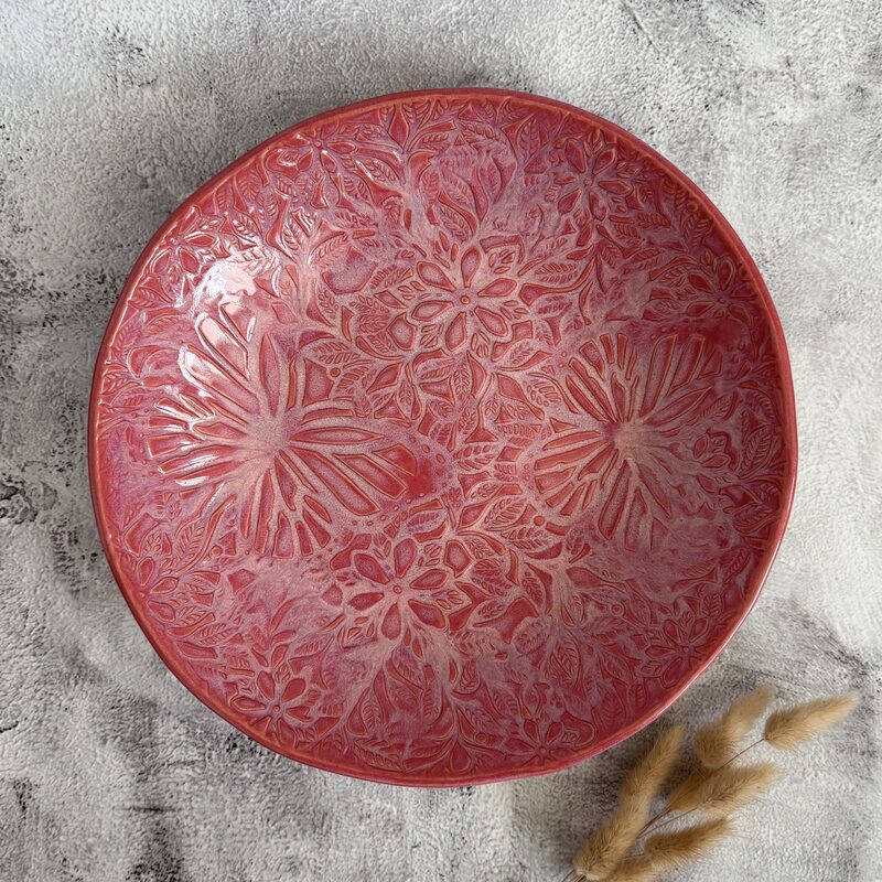Large round red ceramic platter with flower pattern